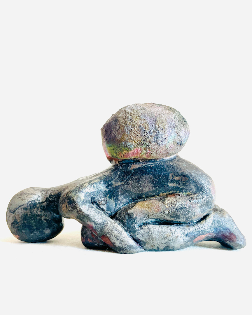 A clay sculpture of a human-like character supporting a stone on their knees, with several different shades and tones across the surface.